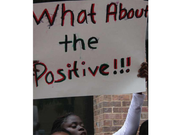 Girl holding sign that says What About the Positive